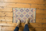Playful vintage Jijim rug mat with geometric diamond and hook designs in soft pastel shades.