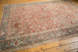 Distressed Heriz carpet corner with textured blush rose and geometric dusty blue, ivory border.
