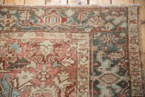 Corner of vintage Heriz carpet, geometric blush, ivory, and blue patterns, even wear.