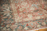 Distressed Heriz carpet detail: geometric border in faded blush, ivory, and dusty blue.