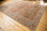 Distressed Afshar carpet with chestnut rust and pale blue geometric medallions, showing even wear.