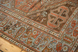 Distressed Afshar rug corner detail, revealing geometric borders in chestnut rust and powder blue.