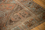 Distressed Afshar rug corner, softened pile, geometric patterns in rust, blue, brown.