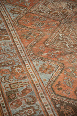 Distressed Afshar carpet, geometric patterns in chestnut rust, pale blue, brown tones.