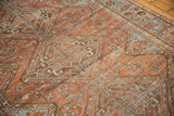 Textured chestnut rust and pale blue Afshar carpet, showing distressed geometric patterns.