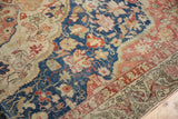 Distressed Sivas rug close-up, revealing worn navy field with blush floral motifs and exposed knot heads.