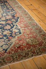 Distressed corner of a Turkish Sivas rug with navy, blush, and antique ivory floral borders.