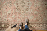 Pale blush, antique ivory, and brown curvilinear motifs on a distressed vintage Oushak rug.