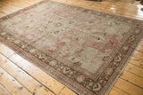 Corner of vintage distressed Oushak rug showing chocolate brown border and pale blush tones.
