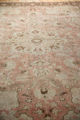 Distressed texture of a vintage Oushak rug in pale blush, antique ivory, and brown.