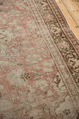 Textured pile of a vintage Oushak with pale blush field, ivory patterns, and brown border.