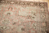 Distressed Oushak rug texture showing pale blush, ivory, and chocolate brown floral motifs.