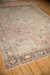 Distressed vintage Oushak carpet corner with blush, ivory, chocolate floral motif and fringe.
