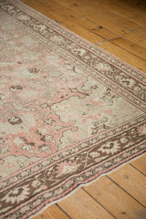Decorative distressed Oushak rug with faded blush, ivory, and chocolate brown pattern.