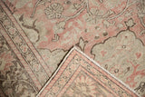 Folded corner of distressed Oushak rug showing soft, worn pale blush pile and hand knotted foundation.
