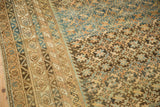Antique Caucasian carpet, intricate geometric border and starburst motifs in muted gold, blue, navy.