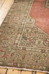 Corner detail of distressed Tabriz rug, showing dusty blush rose field, Samovar border, and ivory fringe.