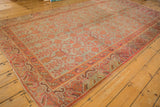 Distressed Khotan rug corner with textured pile, faded sea foam green, and tangerine pomegranate motifs.