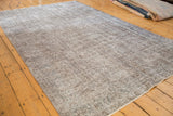 Distressed vintage Turkish Sparta carpet with subtle floral motif and soft silver-gray tones.