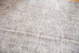 Close-up of hand-knotted Turkish Sparta rug, subtle floral design, oxidized silver, charcoal, and worn texture.