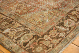 Distressed Mahal carpet corner reveals Herati motif, bold border, and time-softened brown, terracotta tones.