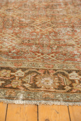 Distressed texture of a Mahal carpet border with terracotta and brown tones and fringe.