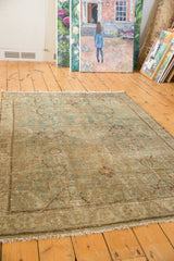 Distressed vintage Hamadan rug corner, highlighting faded seafoam green arabesque border and fringe.