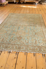Fringed edge of a vintage distressed Hamadan rug, showing green border and foundation wear.