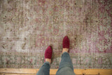 Distressed vintage Sivas rug pile, showing faded raspberry red florals and exposed foundation.