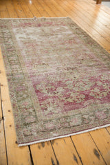 Faded cochineal red and dusty green blossomed floral motifs on a distressed Sivas rug.