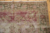 Distressed Sivas rug close-up with exposed foundation, faded raspberry red and green florals.