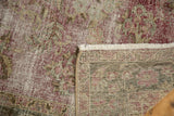 Distressed Sivas rug's worn raspberry red, green pile, exposed foundation, and ivory fringe detail.