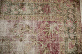 Distressed vintage Sivas rug showing exposed foundation with faded red and green florals.