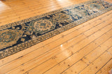 Visible wear and primitive geometric medallions on a dark blue antique Persian runner.