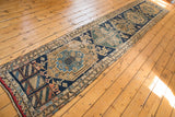 Fringe and geometric patterns in navy, beige, and madder red on antique Persian runner, showing wear.