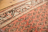 Low pile, brick red field, and repeating mir boteh pattern of the vintage Persian rug.