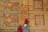 Detail of a vintage distressed Jijim rug, with geometric patterns in saffron, gold, and tangerine.