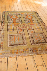 Distressed Jijim rug lower right, showing geometric saffron patterns, fringe, and light staining.