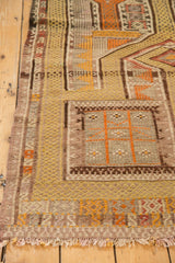 Close-up of vintage Jijim rug with geometric tangerine, dusty gold, and charcoal woven patterns.