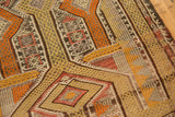 Distressed hand-woven Jijim rug texture with geometric motifs in saffron, tangerine, and charcoal.