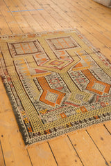 Distressed bottom corner of Turkish Jijim rug, saffron and tangerine geometric patterns, light staining.