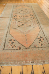 Oushak rug corner: distressed apricot peach pinwheels, silver field, and floral border detail.