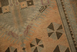 Apricot peach field with charcoal pinwheel, pale mauve motifs, and distressed, low pile texture.