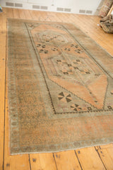 Decorative floral and tendril motifs on the distressed apricot Oushak rug border.
