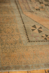 Distressed Oushak runner's low pile, soft apricot peach tones, and detailed scrolled tendril border.