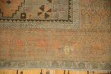 Distressed vintage Oushak rug corner with apricot peach, charcoal patterns, and low pile texture.
