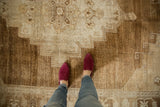 Low pile and worn texture of distressed Oushak rug in sand and bronze tones.