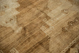 Distressed Oushak carpet close-up, highlighting primitive beige patterns and heavily abrashed texture.