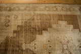 Distressed Oushak rug showing abrash, stepped medallion, and border in muted ivory and sand.