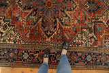Heriz carpet's complex pattern of serrated leaves, blossoms, and geometric motifs in cherry red.